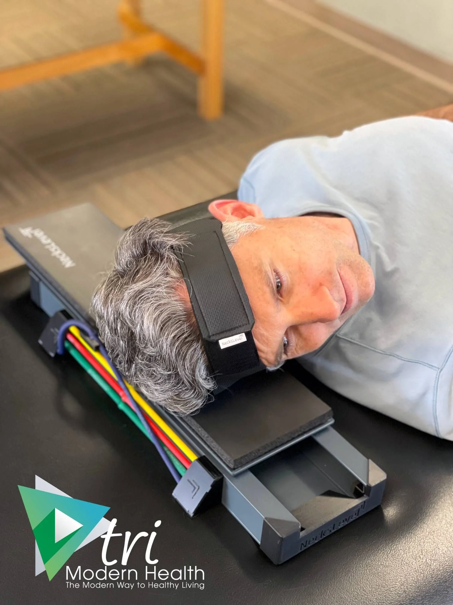 Patient using a NeckPro cervical traction device while lying on a treatment table at Tri Modern Health chiropractic clinic
