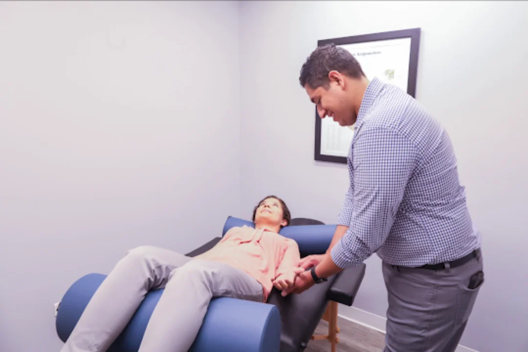 Chiropractor performing a wrist or hand adjustment on a patient reclining in a treatment chair during a chiropractic consultation
